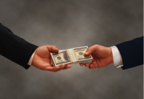 Two hands of businessmen passing a stack of dollars